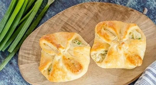 Freshly baked chicken cream cheese croissants on a wooden board