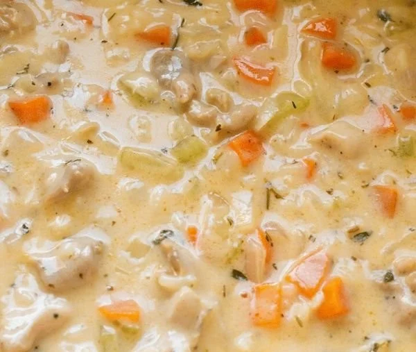 A bowl of creamy chicken and rice soup with fresh herbs and vegetables