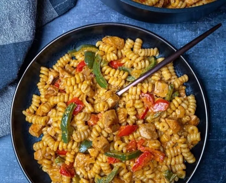 Delicious creamy chicken fajita pasta served in a bowl with fresh vegetables.