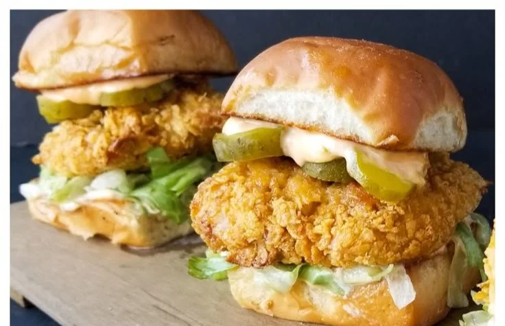 Fried chicken sliders on a platter with toppings and sauces