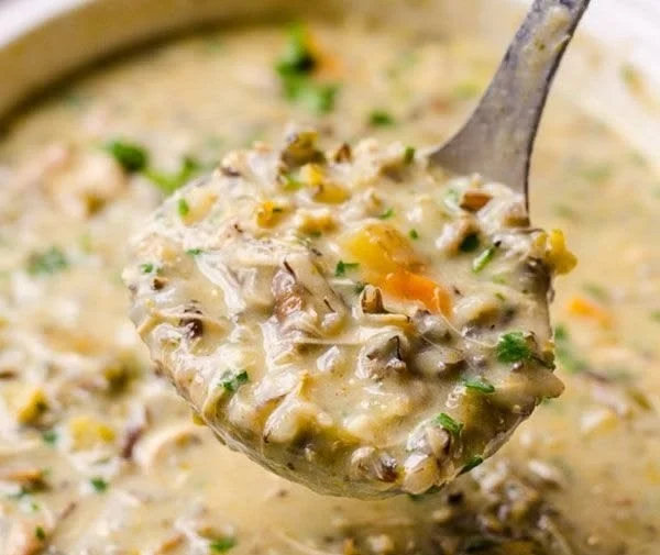 Healthy chicken wild rice soup in a bowl with vegetables and herbs
