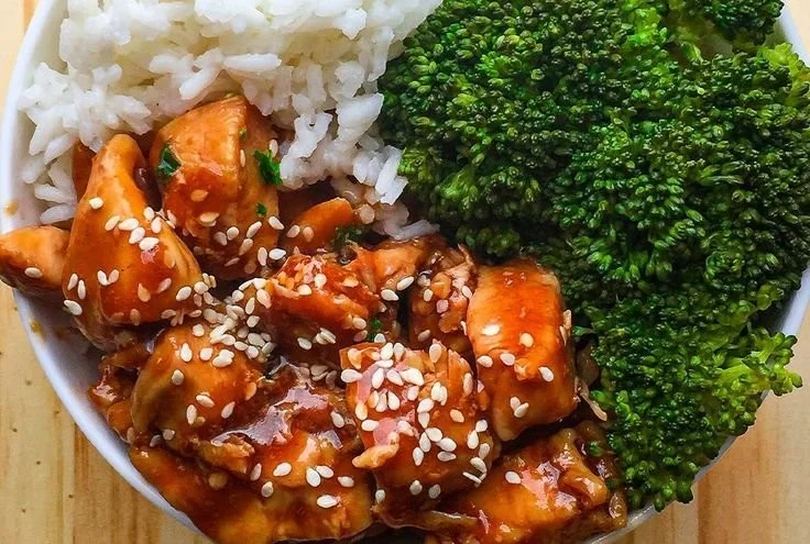 Delicious teriyaki chicken rice bowl topped with fresh vegetables and sesame seeds.